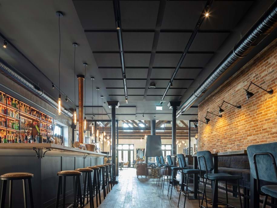 Glued acoustic ceiling in hotel bar with brick wall