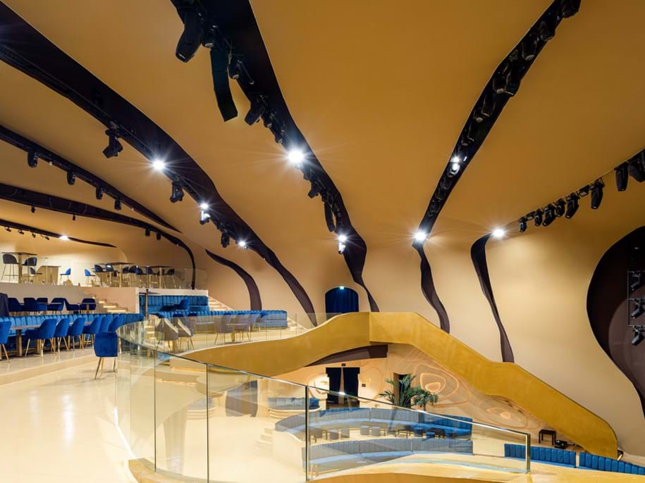 Intérieur d'une boîte de nuit moderne présentant un design organique avec des structures courbes de couleur marron clair au plafond et sur les murs.