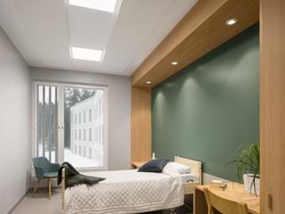 White acoustic ceiling in psychiatric clinic patient room  with wooden interior details and furniture and a dark green wall