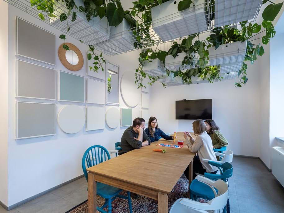 Lidé v zasedací místnosti s čtvercovými a kulatými akustickými absorbéry na stěnách