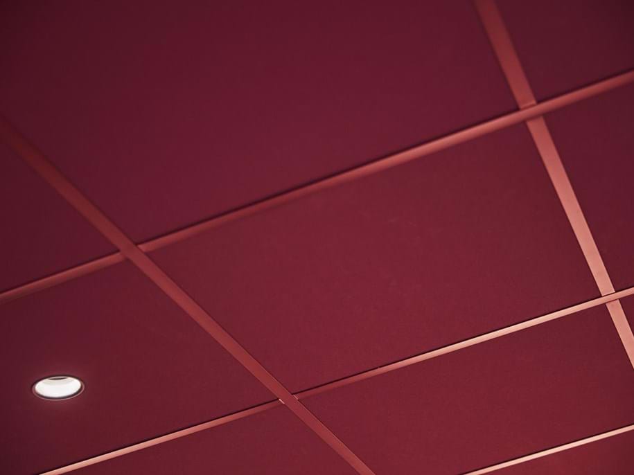 Close-up of dark red suspended acoustic ceiling with matching grids