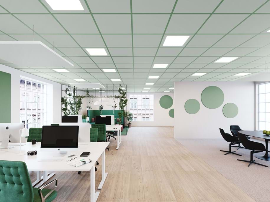 A modern, spacious office with white desks and green chairs. The room features a wooden floor, green and white walls with circular decorations, and large windows allowing natural light. Indoor plants add a touch of greenery.