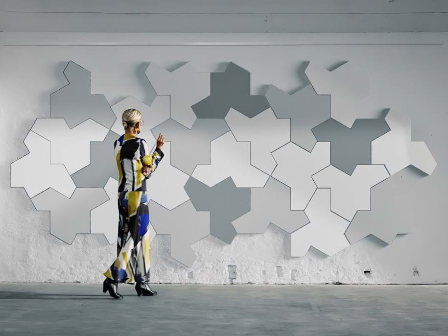 Una donna osserva il muro decorato con pannelli acustici a forma di puzzle