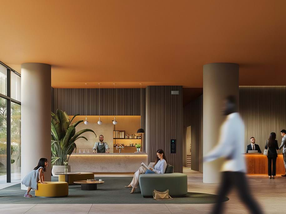 Interior of a modern hotel lobby with warm lighting. The ceiling and some walls are painted in a muted orange hue, while other walls feature vertical wooden slats. In the foreground, there is a blurred figure walking past, suggesting movement within the space. The central area has a seating arrangement with two individuals seated on low-profile furniture; a child on a mustard yellow ottoman and a woman on a beige sofa. To the right, there's a reception desk where an employee stands ready behind the counter and two individuals appear to be checking in or conversing with the staff member. The overall atmosphere conveys a sense of contemporary design blended with comfort and activity.