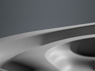 Close-up view of a smooth, curved surface with subtle gradients of light and shadow, creating an abstract monochromatic landscape.
