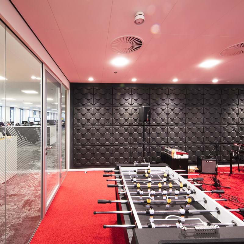 Rozā, piekārtie akustiskie griesti biroja spēļu un mūzikas istabā ar sarkanu paklāju un melnām sienu dekorācijām