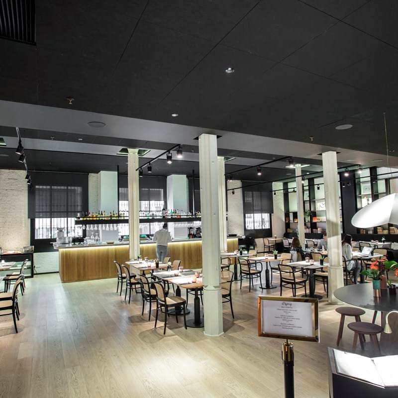 Melni, piekaramie akustiskie griesti restorānā ar bāru, ko ieskauj galdi un krēsli