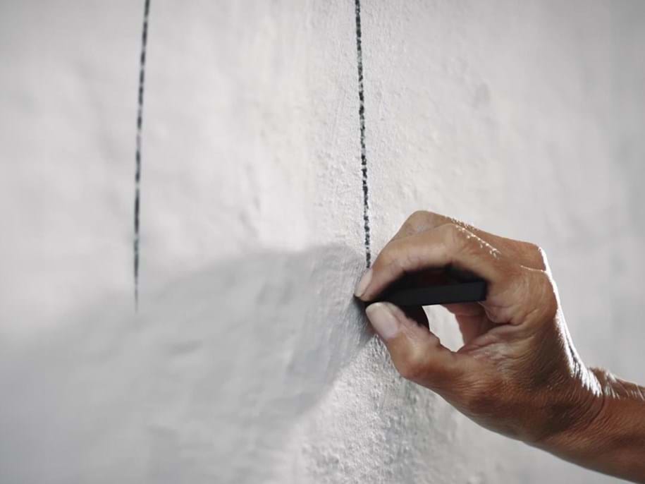 Nahaufnahme einer Hand, die eine Skizze an einer Wand anfertigt