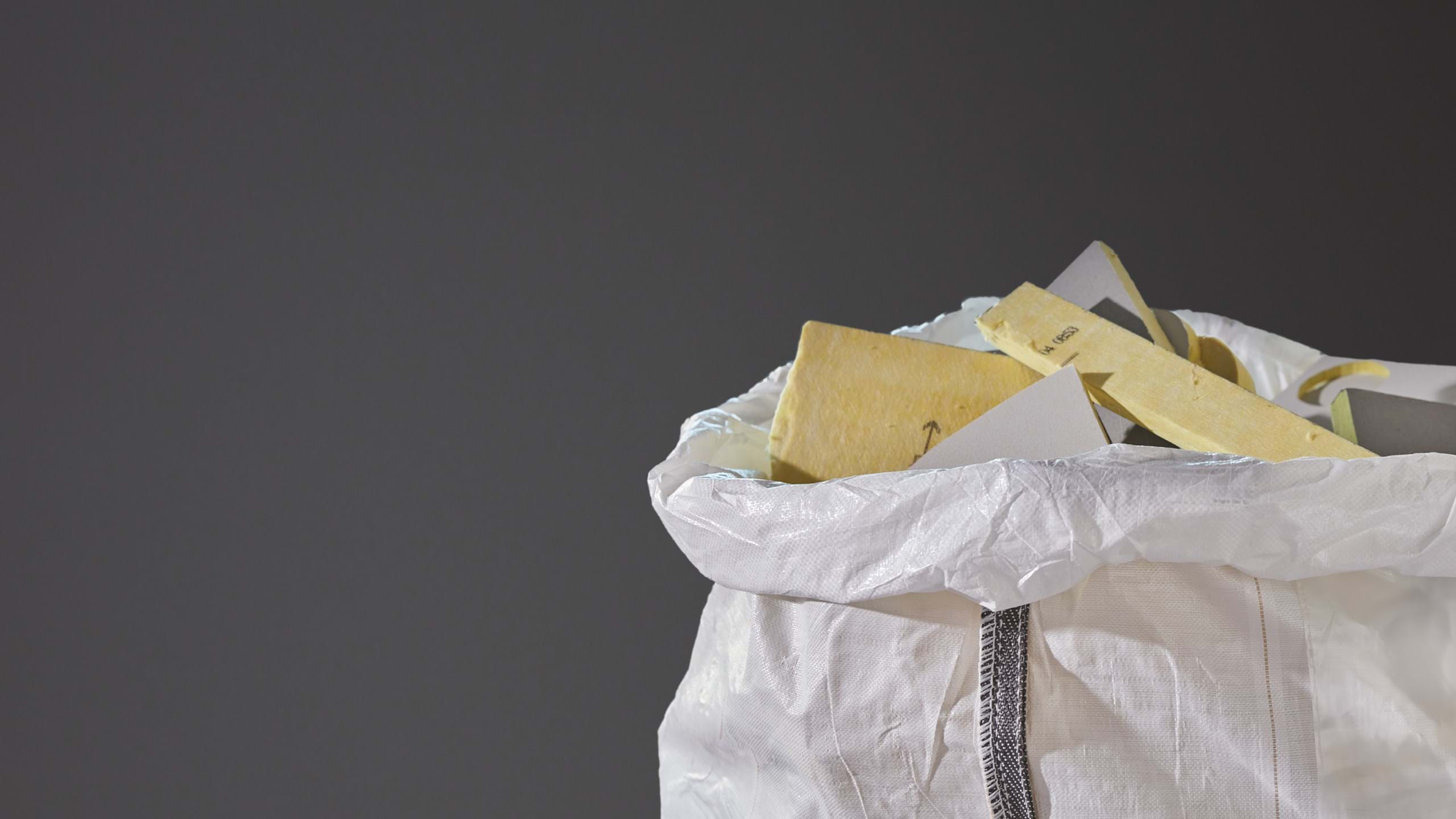 Close-up of a white plastic bag filled with used acoustic glasswool panels