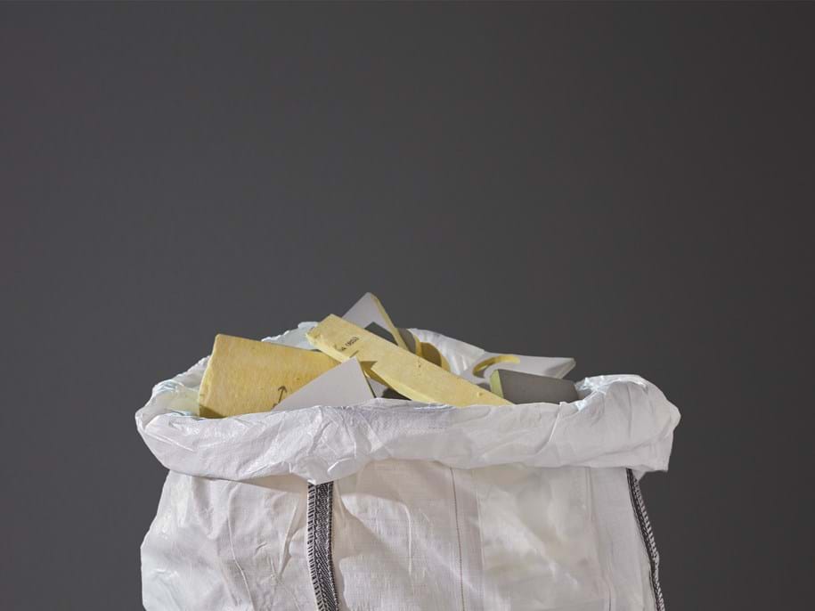Close-up of a white plastic bag filled with used acoustic glasswool panels