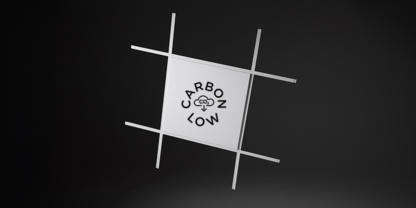 A white acoustic panel in a grid system on a black background. A logotype saying "Carbon low" is visible on the panel.