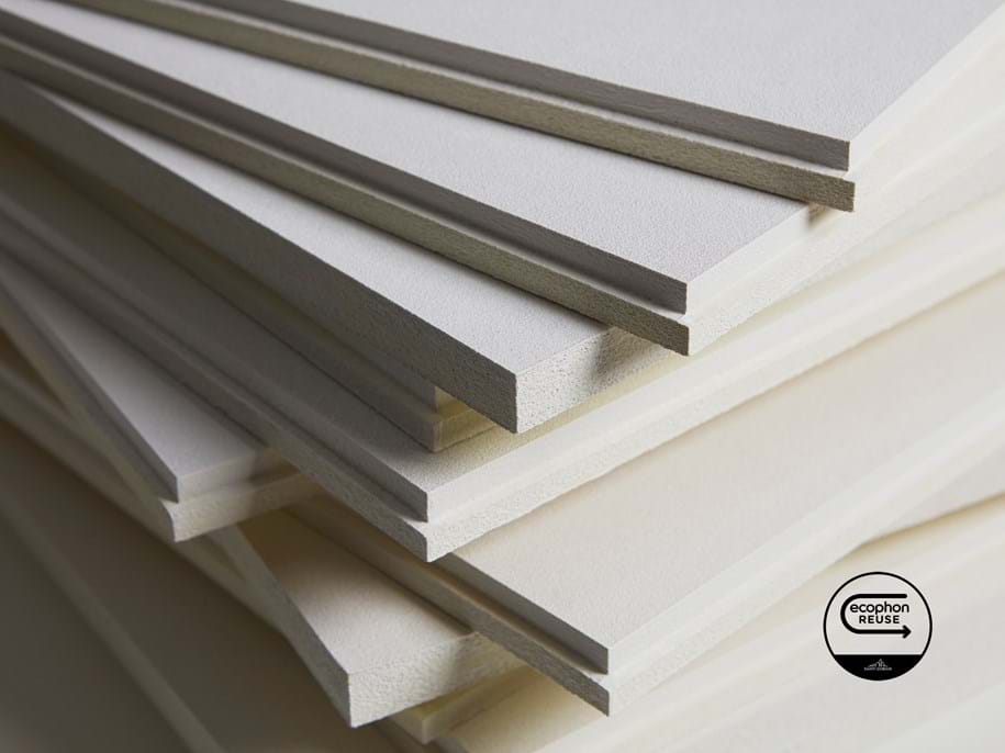 Close-up of a pile of white acoustic panels and a logotype in the bottom right corner